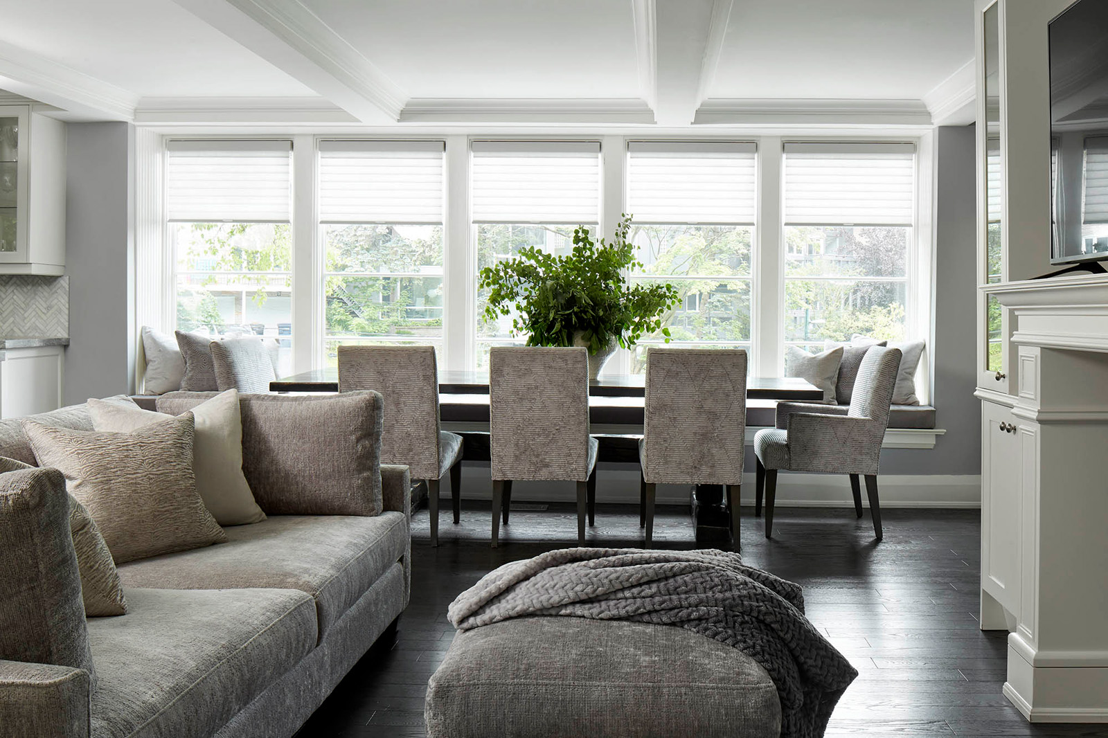 NUITH – FIFTY SHADES OF DIOR GRAY – FAMILY ROOM DESIGNED BY CELIA ALIDA RUTTE – PHOTOS BY DONNA GRIFFITH A family room designed in shades of purple grey with a large sofa, an ottoman, a large dining table in front of a window bench and five dining chairs.