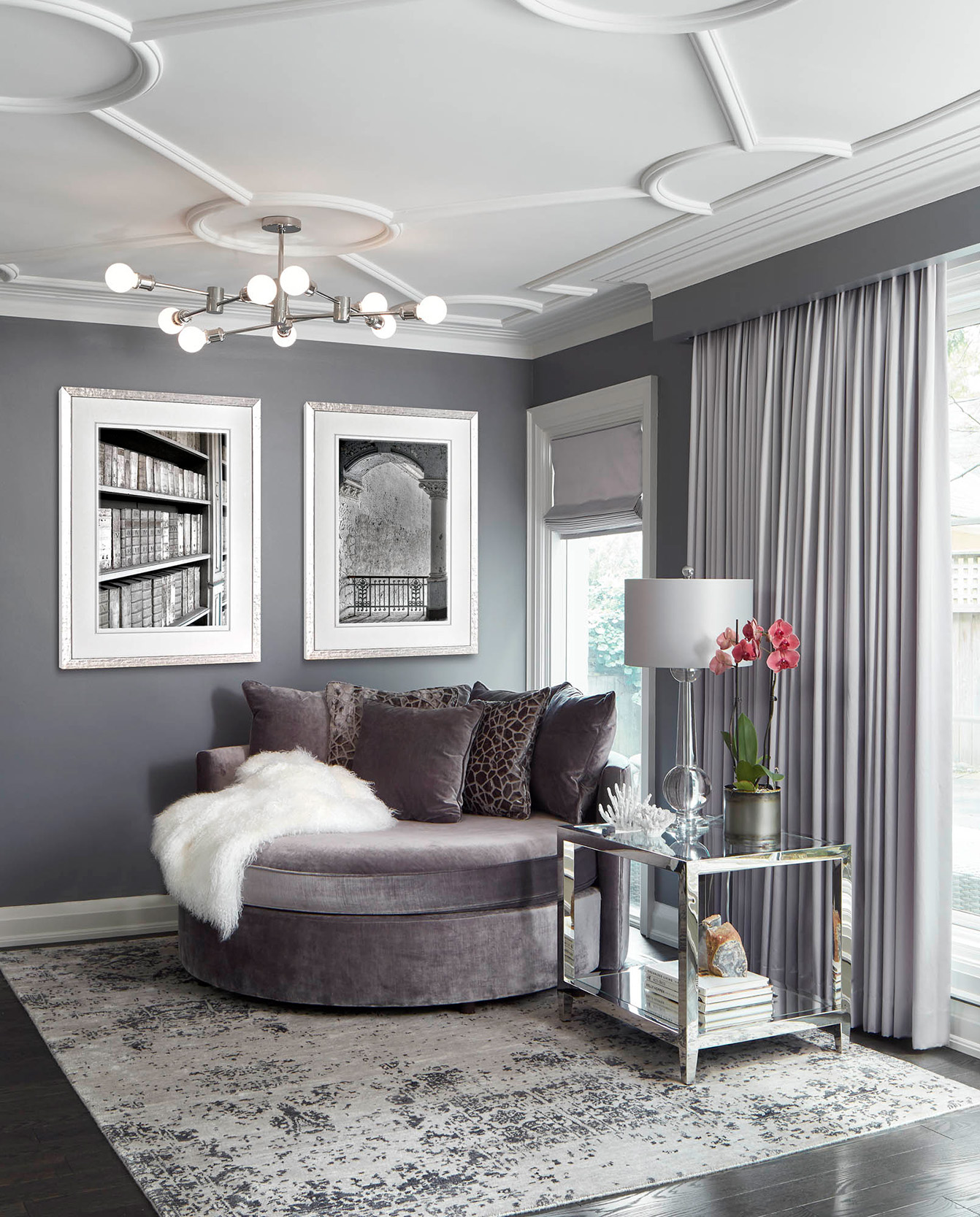 NUITH – FIFTY SHADES OF DIOR GRAY – READING NOOK DESIGNED BY CELIA ALIDA RUTTE – PHOTOS BY DONNA GRIFFITH A reading nook designed in shades of purple grey with artwork on the walls, a large round reading chair, a side table, floor to ceiling drapery and an area rug.