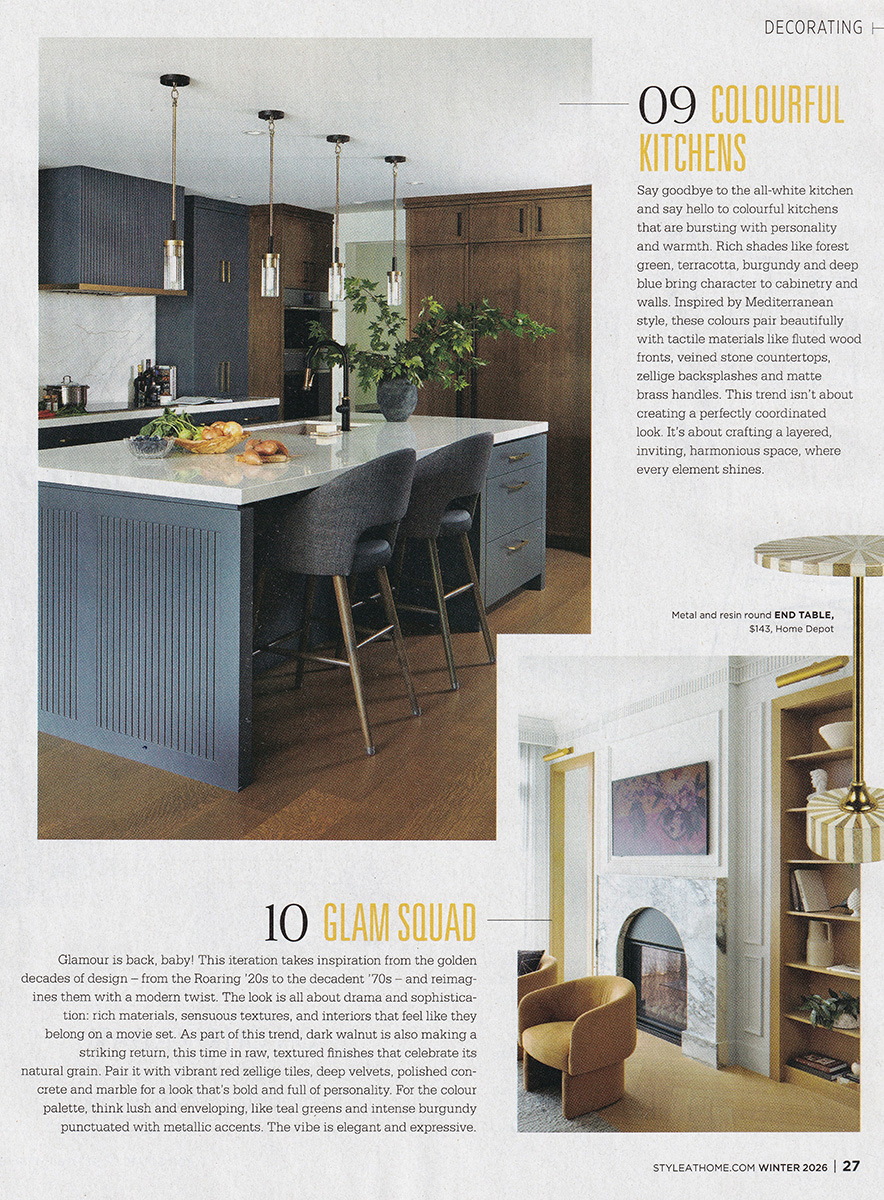A tear sheet from Style at Home magazine showcasing a kitchen with a large island and cabinetry in a combination of dark blue and warm caramel wood tones.